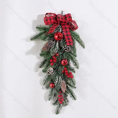 a christmas wreath with pine cones and red berries hanging on a white wall in the corner