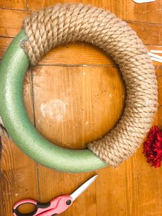 a green wreath sitting on top of a wooden table next to some scissors and yarn