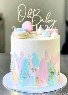 a white cake with pink, blue and yellow frosting on top that says out baby