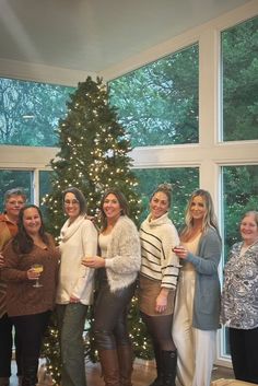 a group of women standing in front of a christmas tree