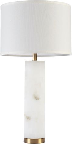 a white table lamp with a gold base and a white drum light shade on top