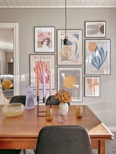 a dining room table with chairs and pictures on the wall above it, along with candles