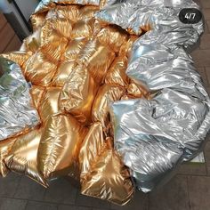 a pile of silver and gold foil sitting on top of a floor next to a refrigerator