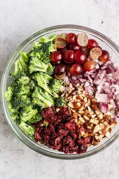 a bowl filled with broccoli, cranberries, nuts and other vegetables