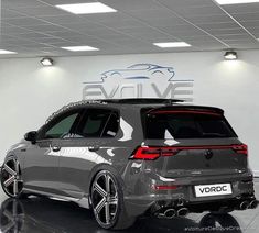 the rear end of a grey volkswagen vehicle in a showroom with white walls and black flooring