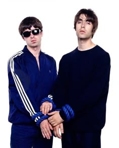 two men standing next to each other in front of a white background with sunglasses on