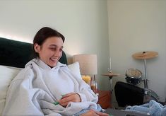 a woman wrapped in a blanket sitting on a bed with a laptop computer next to her