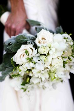 a bride holding a bouquet of white flowers