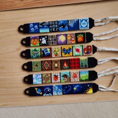 four lanyards with different designs on them sitting on a wooden table next to a pair of scissors