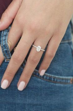 a close up of a person's hand with a ring on their finger and jeans