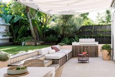 an outdoor living area with couches, table and grill