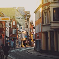 a person walking down the street in front of some buildings with shops on each side