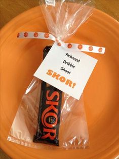 a candy bar wrapped in cellophane on an orange plate with a plastic bag