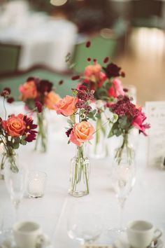 several vases filled with flowers sitting on top of a white tablecloth covered table