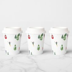 three coffee cups sitting on top of a marble counter next to each other with christmas decorations