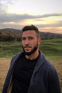 a man with a beard standing in front of a field