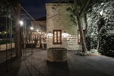 a stone building with trees and lights on the outside at night in front of it