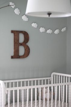 a baby's nursery room with clouds hanging from the ceiling and a crib