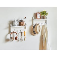 two white shelves with hats, keys and other items hanging on the wall above them