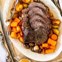 a white plate topped with meat, potatoes and carrots on top of a table