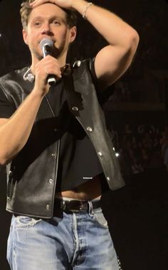 a man holding a microphone up to his head while standing in front of a crowd