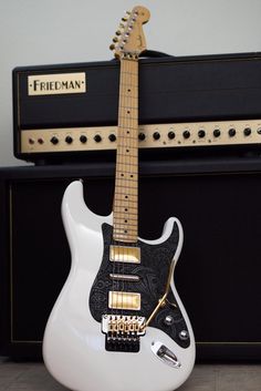 a white electric guitar sitting next to an amp