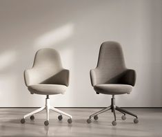 two office chairs sitting next to each other on casteors in front of a white wall