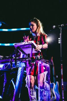 a woman standing in front of a keyboard on stage