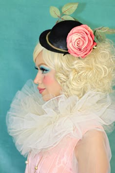 a woman with blonde hair wearing a black hat and pink rose on her head,