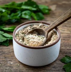 a wooden spoon in a white bowl filled with herbs