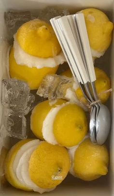 a box filled with lemons next to a whisk and ice cubes