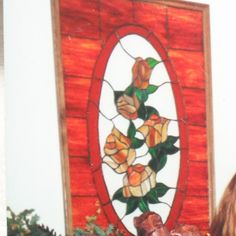 a woman looking at a stained glass window with roses on it and flowers in the background