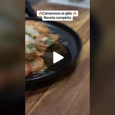 a black plate filled with food on top of a wooden table