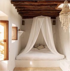 a bed with a white canopy over it in a room next to a door and window