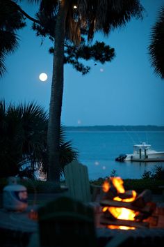 a fire pit sitting next to the ocean at night