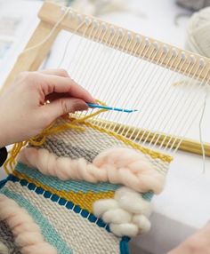 someone is working on an art project with yarn and cotton balls in front of the weaving machine