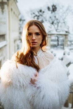 a woman with long hair wearing a white fur coat