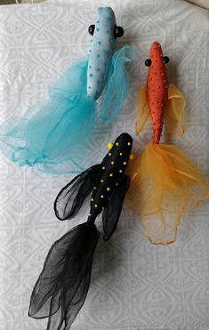 three fish made out of tulle sitting on top of a bed