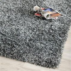 a grey rug with a rolled up magazine on the floor and a pair of sneakers