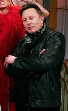 two people standing next to each other in front of a red feathered dress and black leather jacket