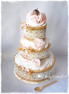 a three tiered wedding cake with pink roses on top and gold trimmings