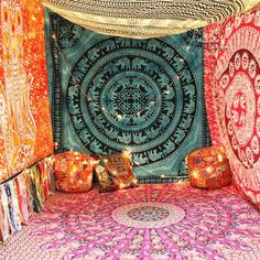 a bed covered in lots of different colored bedspreads and rugs next to each other