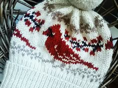 a knitted hat sitting on top of a wicker basket next to a stuffed animal