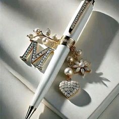 a pen sitting on top of a white table next to some pearls and brooches