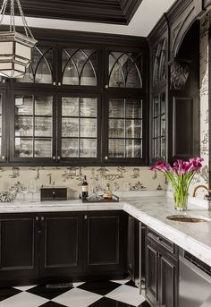 a black and white checkered floor kitchen with glass front cabinets, marble counter tops, and chandelier