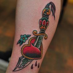 a tattoo on the leg of a woman with a dagger and heart