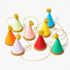 six party hats with pom - poms on them, all in different colors