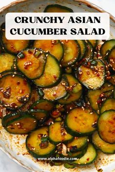 a white bowl filled with sliced cucumbers and topped with sesame seeds on top