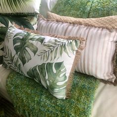 some pillows and blankets on a bed with green carpeted flooring in the background