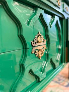 a close up of a green dresser with gold decorations on the top and bottom part